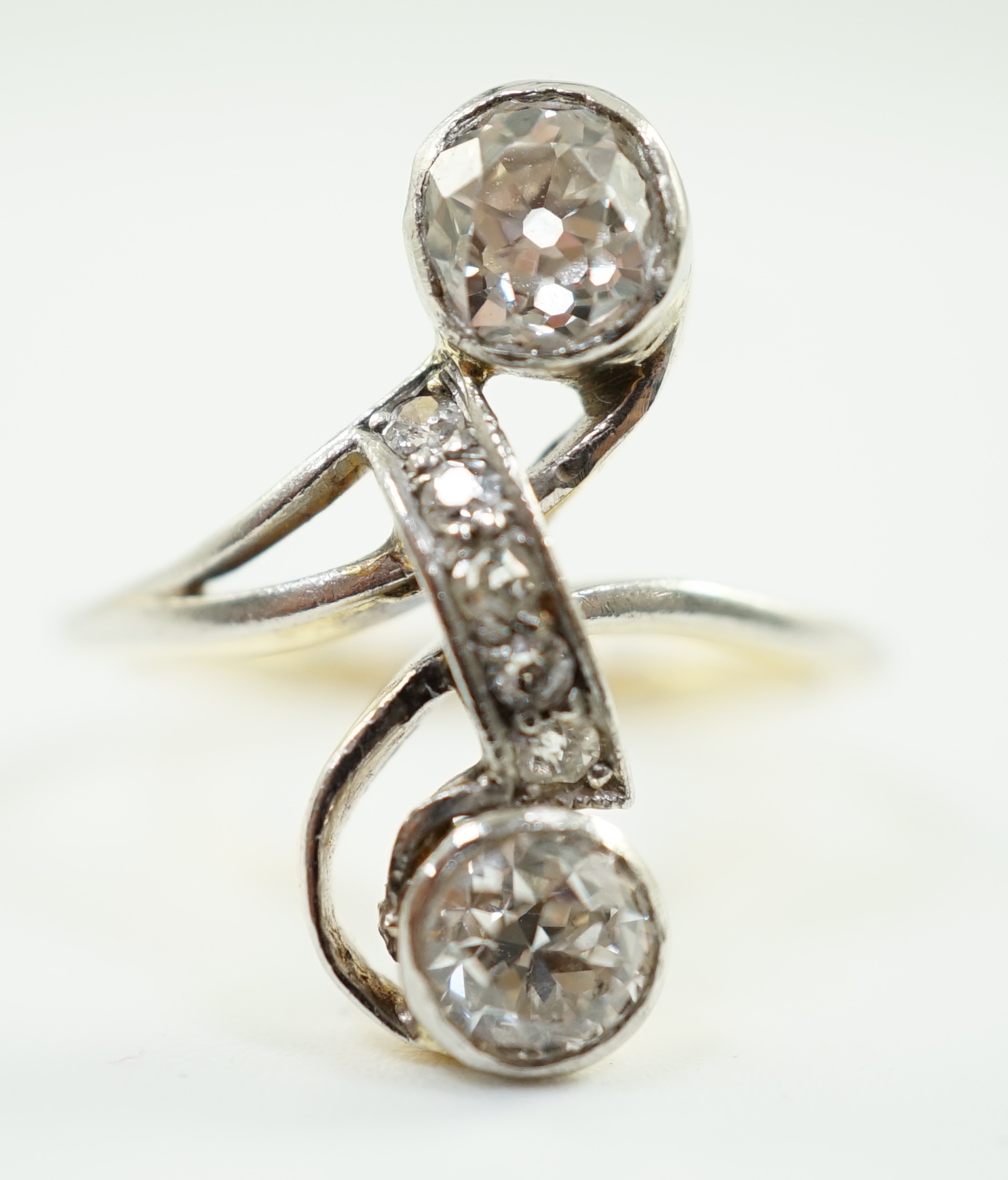 An early to mid 20th century gold and two stone diamond cross over ring, with five stone diamond chip setting